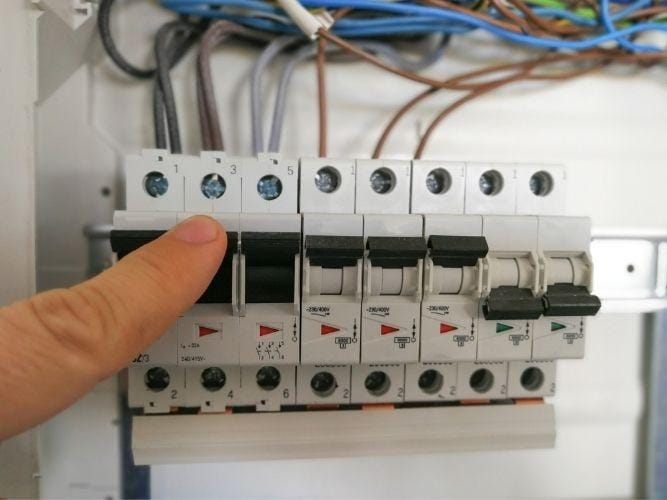 Male finger switching circuit breakers inside electrical panel cabinet 